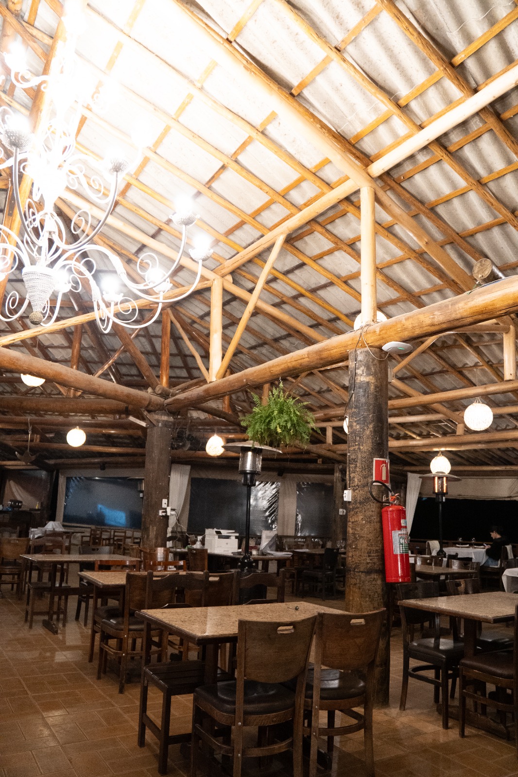 Salão interno do Restaurante das Águas com estrutura de madeira rústica e lustres