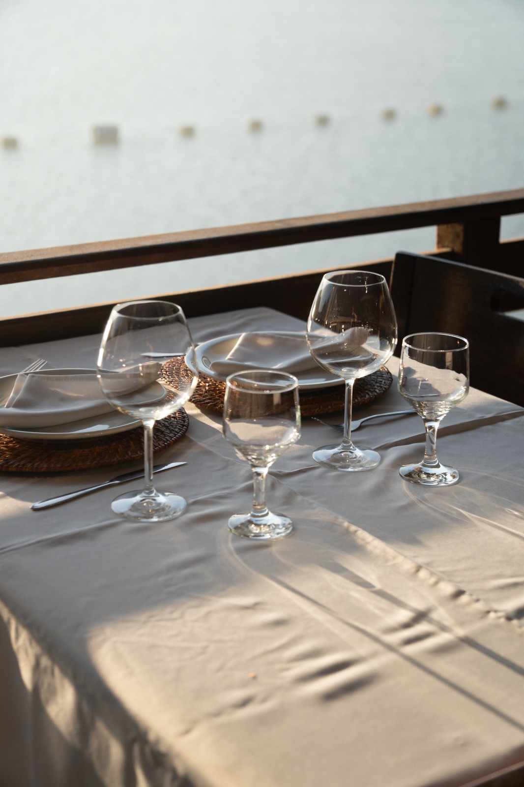 Mesa posta com taças e vista para a represa ao entardecer
